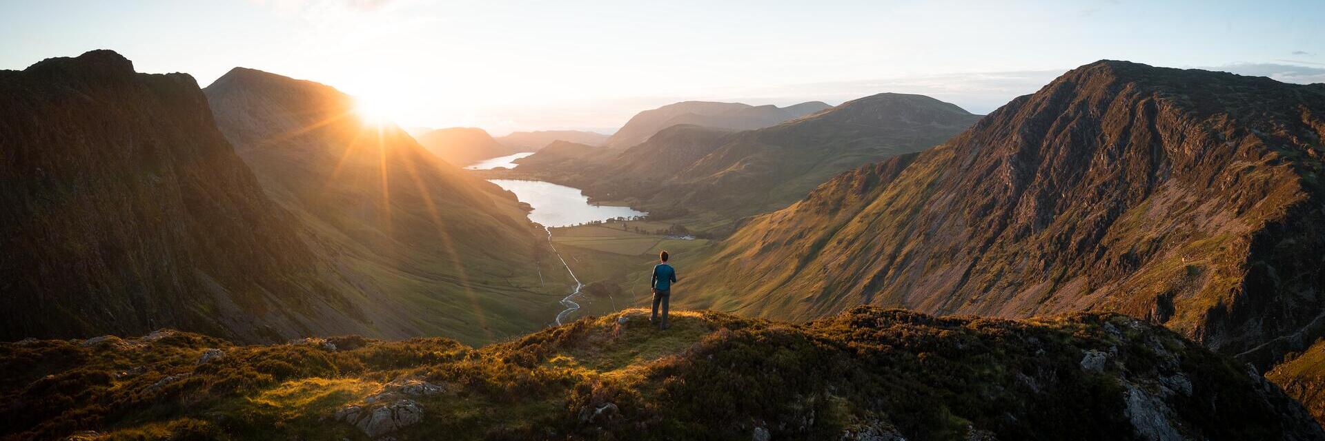 A man stands looking out over a vast lake view