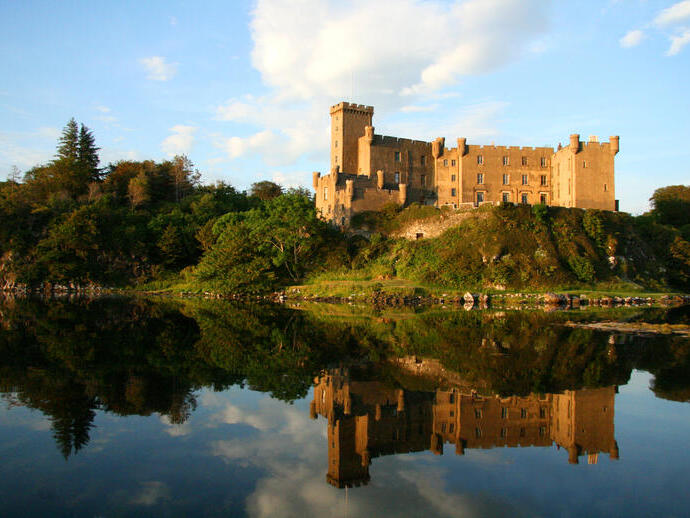 Castello affacciato su una baia, il cui riflesso è visibile nell'acqua