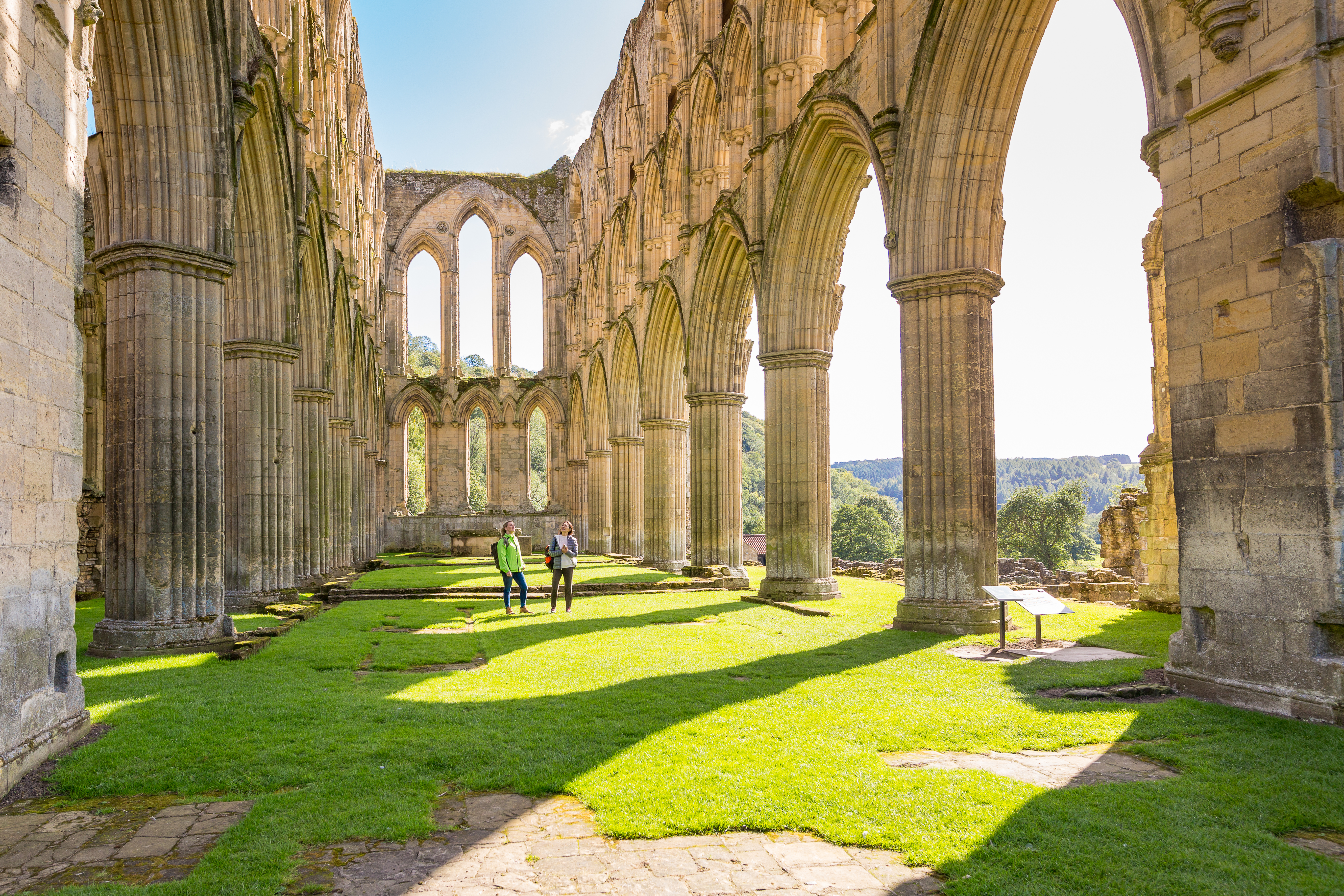 Two female friends in the central nave of a ruined abbey in the sunshine