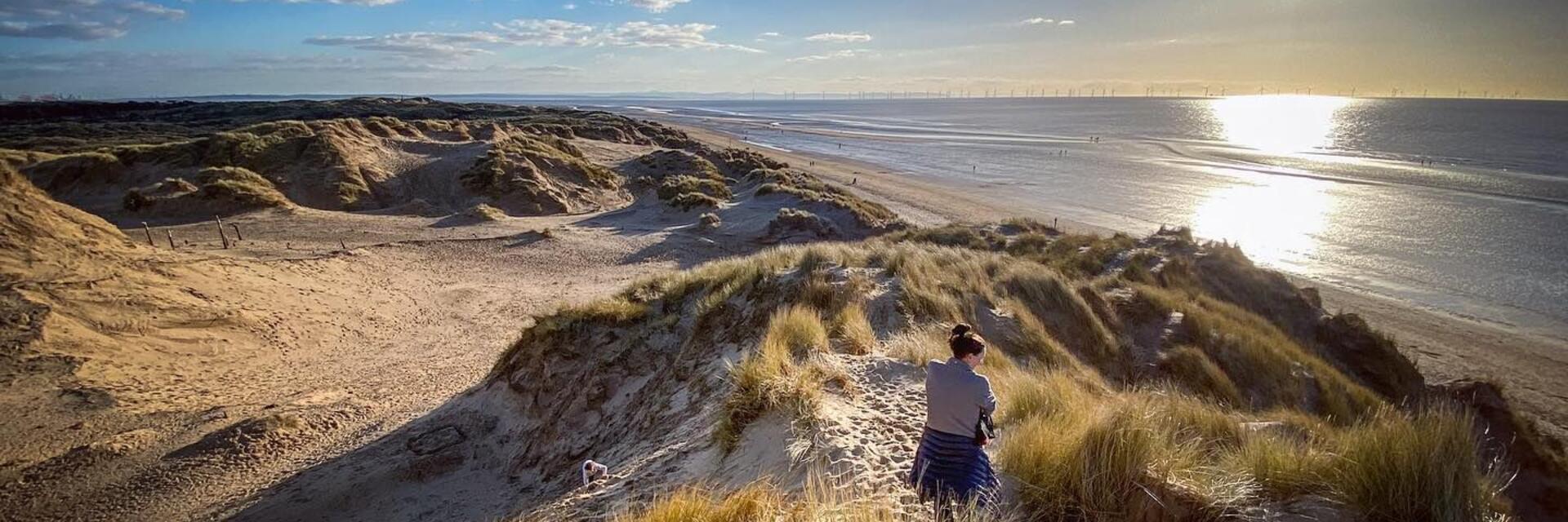 Woman walking along sand dunes at Formby beach