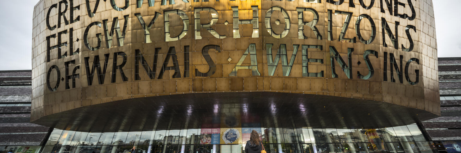 Persona mirando hacia arriba a la fachada de un edificio de bronce