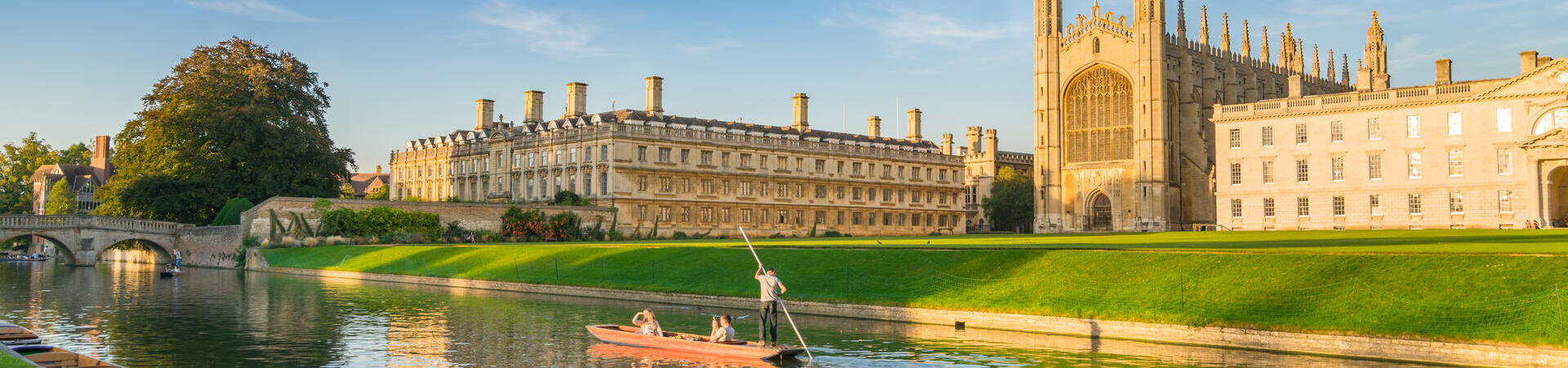 People punting along a river next to a college and chapel.