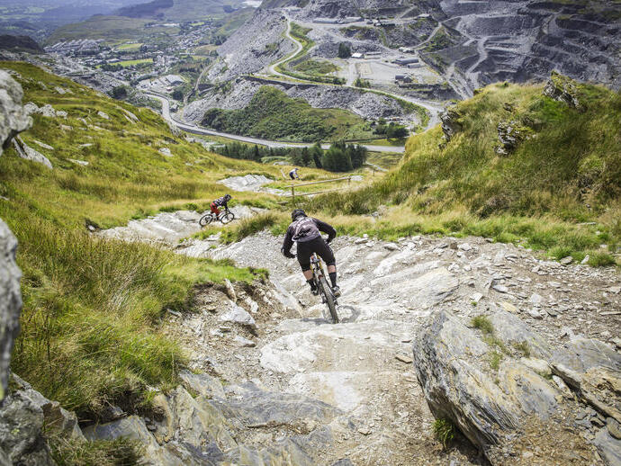 People mountain biking down a steep hill.