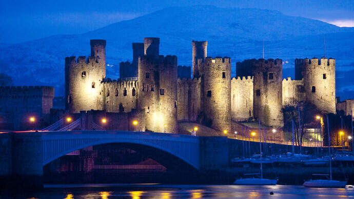A castle lit up at night by the river