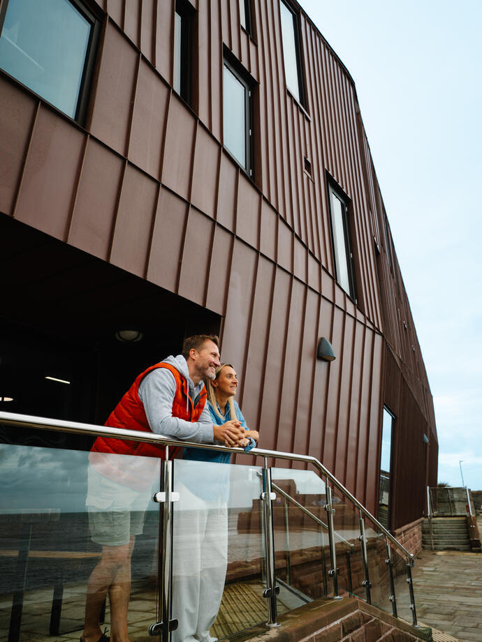 A man and a woman standing on steps in front of a modern building