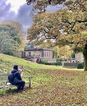 A lady and dog sitting on a bench outside at Lyme Park, Cheshire