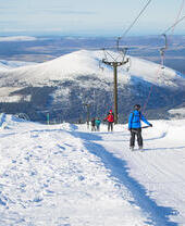 Gruppe von Skifahrern auf einer verschneiten Piste im Cairngorms-Nationalpark, Schottland