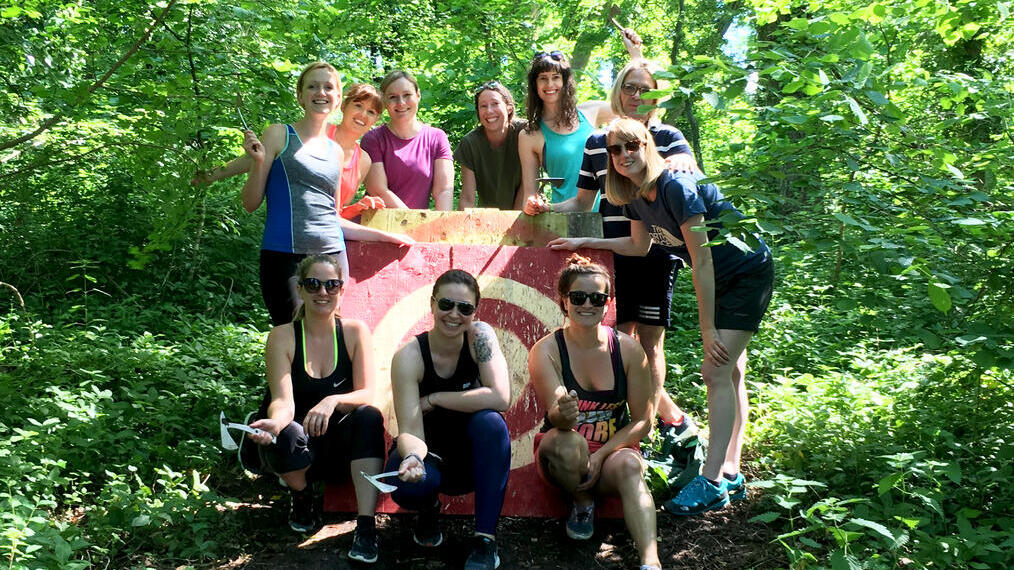 Eine Gruppe von Menschen posiert vor einer Zielscheibe in einer Axtwurf-Anlage in Bristol