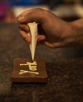 Person, die dunkle Schokolade mit weißer Schokoladenglasur verziert