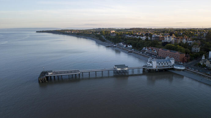 A pier jutting out into the ocean in a large town.