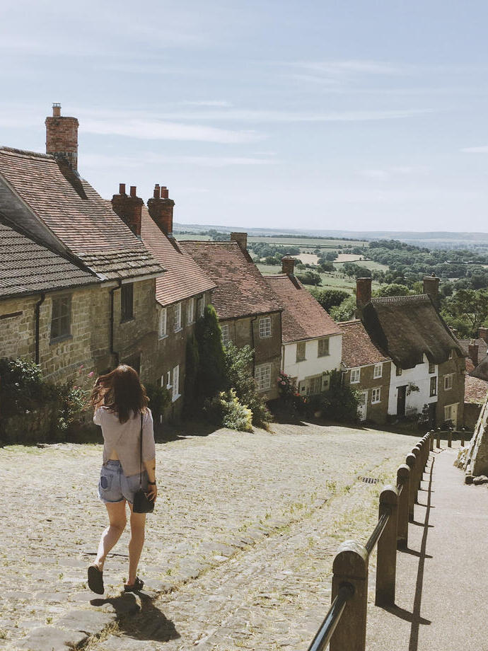 Woman, in shorts, walking down village lane