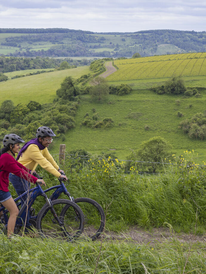 A man and a woman stand with bicycles wearing helmets