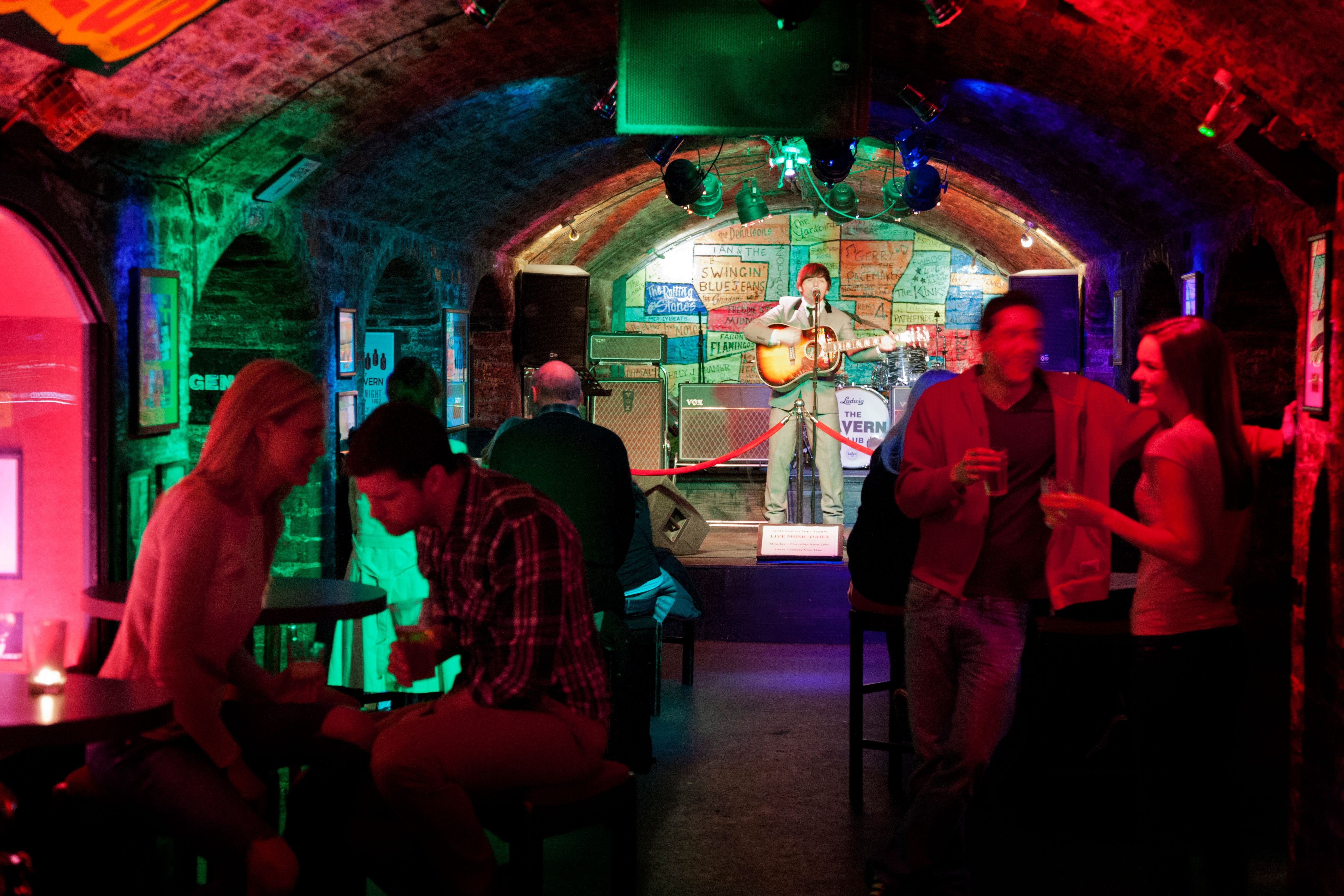 Man on stage playing a guitar in a club with arched ceilings