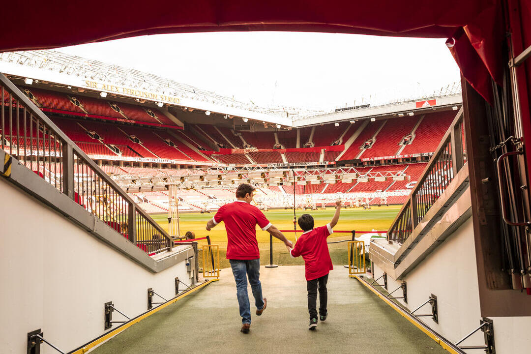 A man and boy in stadium tunnel looking out to pitch