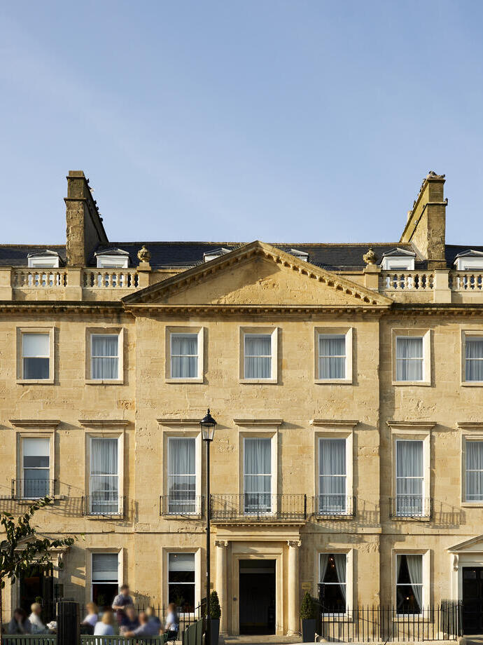 Outside exterior of a large mansion with outside seated courtyard on a clear day.