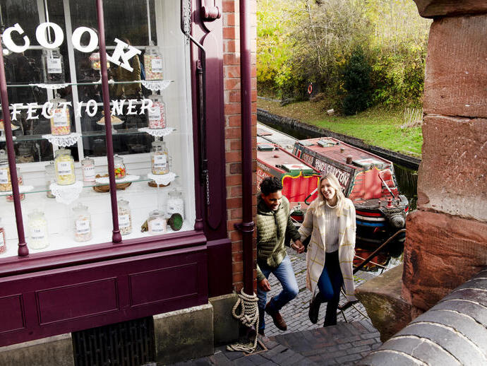 Couple walking up steps by the side of a sweet shop and canal