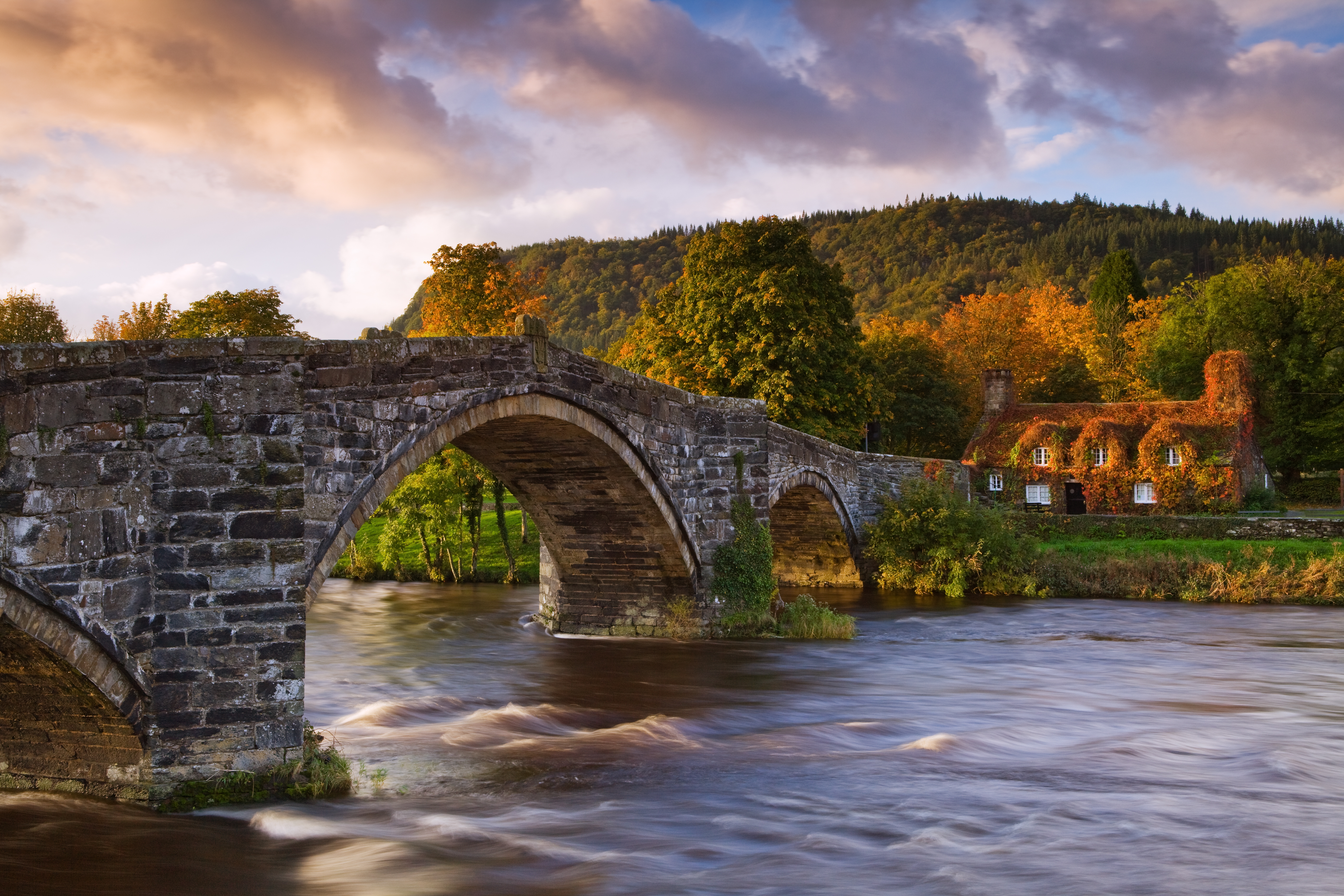 Large stone arched bridge over a flowing river. Sunset