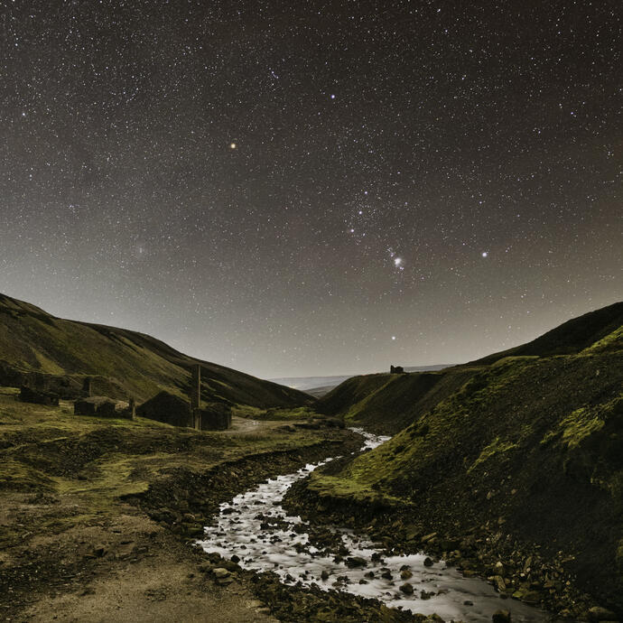 A stream winding through the mountains under a starry sky.