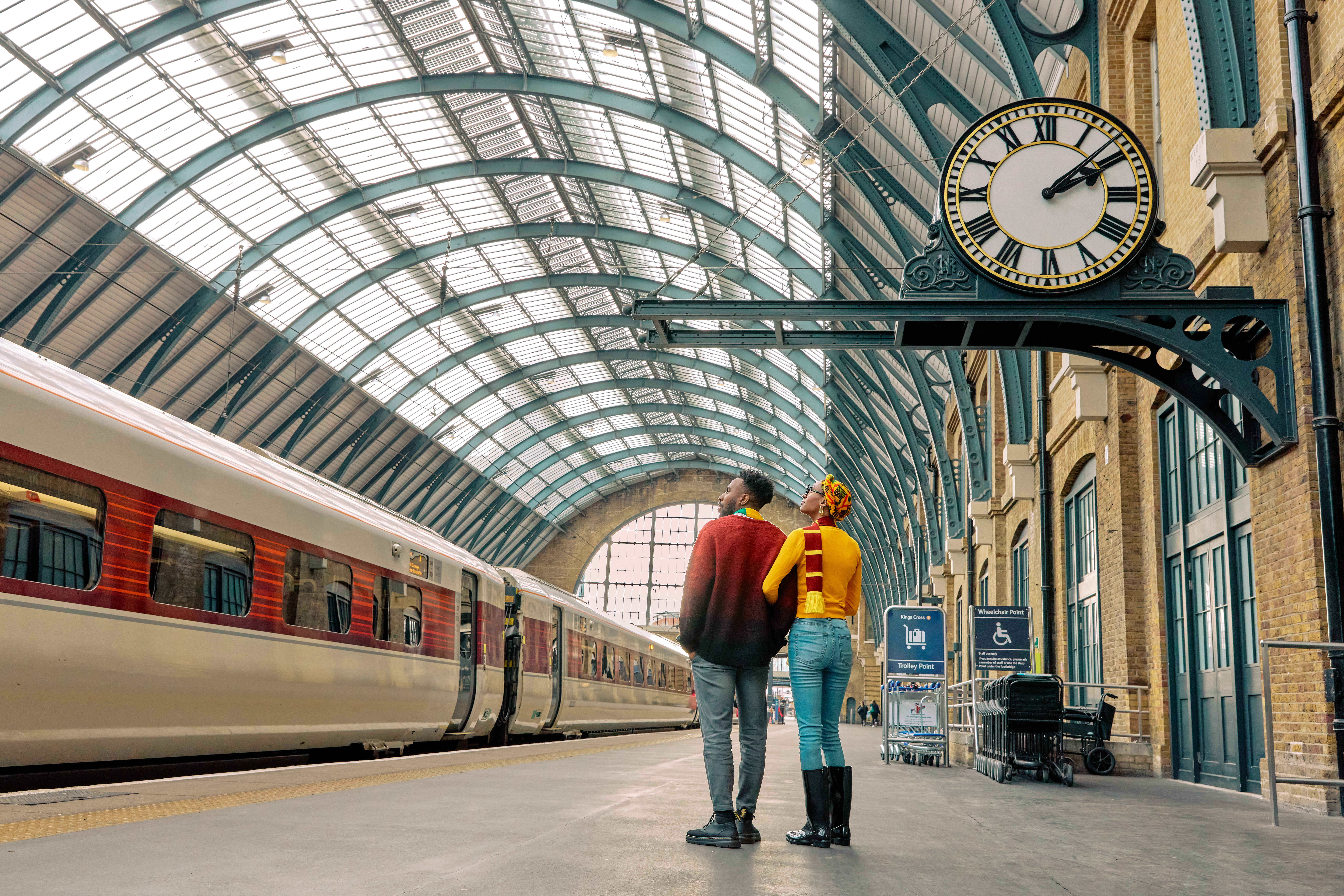 Mann und Frau blicken in einer großen Bahnhofshalle zur Decke hinauf.