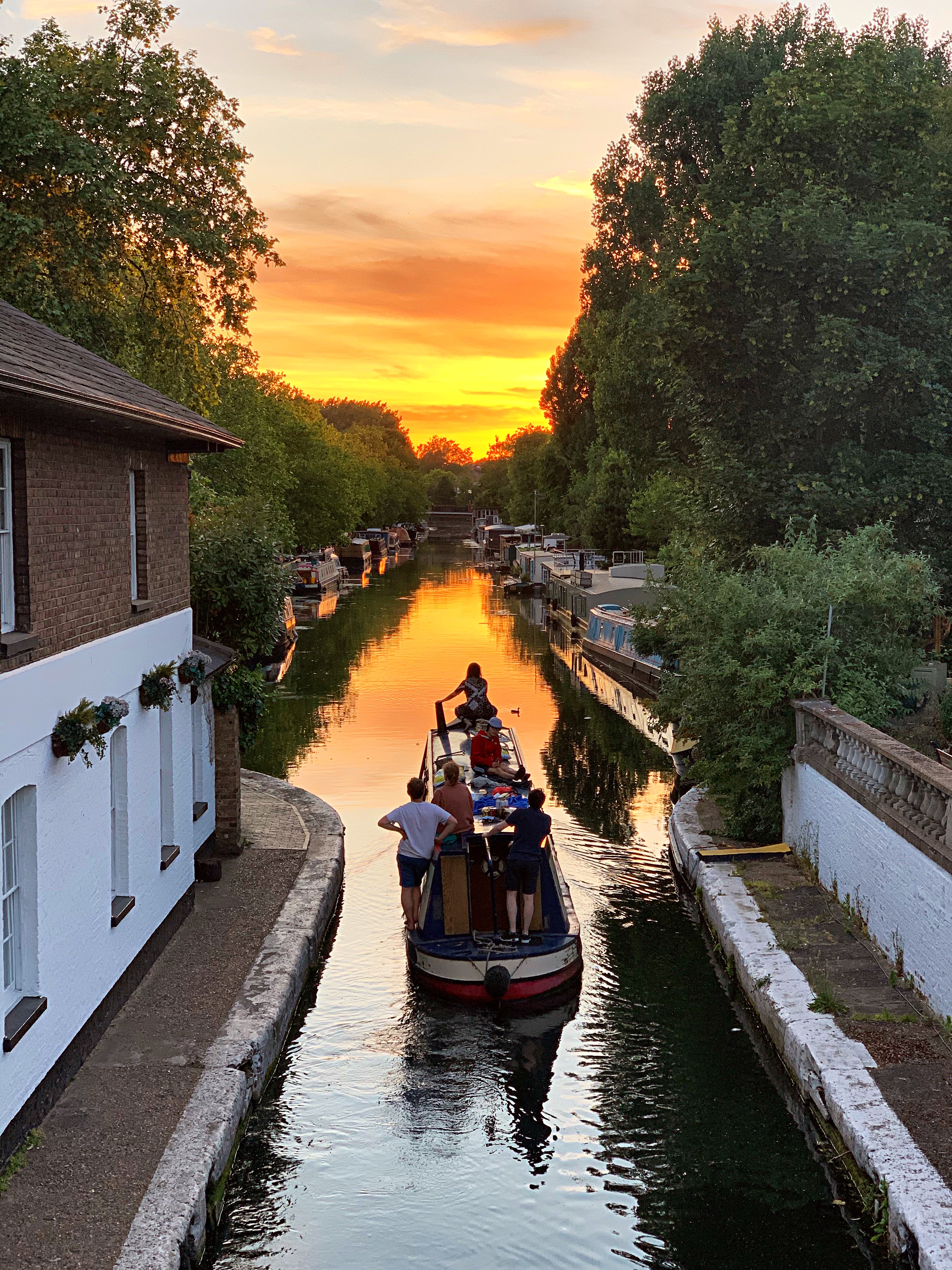 Menschen auf einem schmalen Boot auf einem Kanal bei Sonnenuntergang