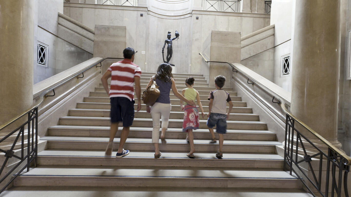Familie mit zwei Kindern, die in einem Museum eine Treppe hinaufsteigen