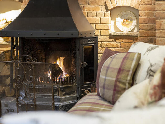 Close-up of the inglenook fireplace with fire and tartan patterned sofas.