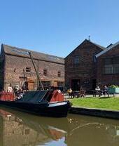 Exterior view of a canal and canalboat outside a Victorian workshop.