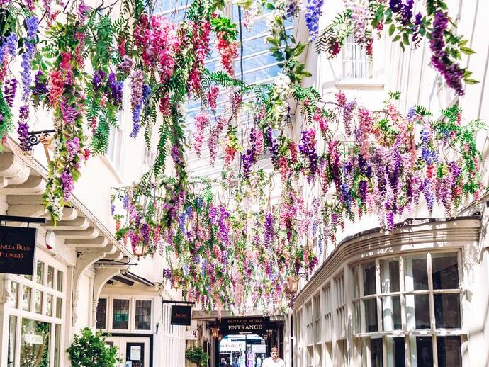 Hombre caminando por un arco cubierto de flores en Lion Walk, Colchester