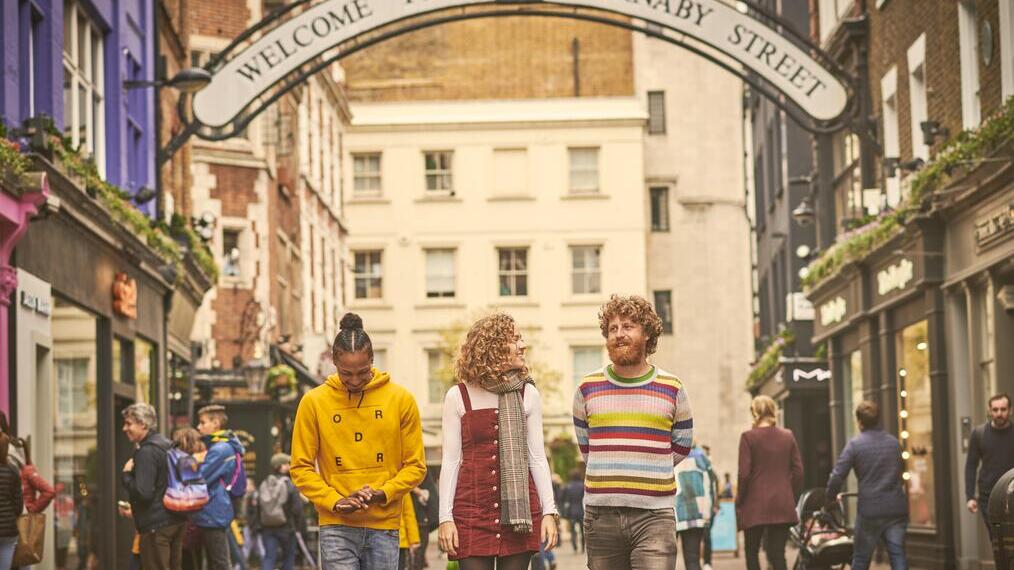Woman and two men walking down a shopping street