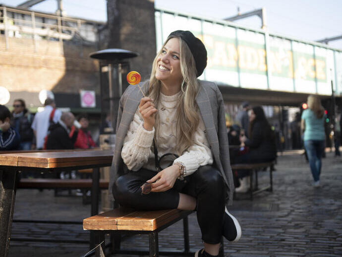 Une femme assise sur un banc, souriante, tenant une sucette