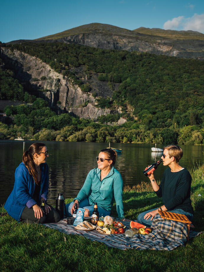 Freunde beim Picknick auf einer Wiese an einem Gletschersee.