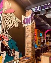 Large wall mural of a funky zebra hodling a cocktail saying "Amazing" inside the bar at CC Blooms.