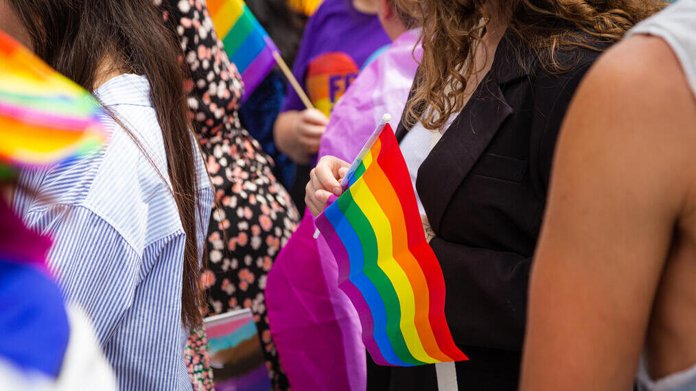 Crowds of people holding rainbow flags at a Pride Parade in London.