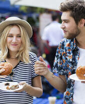 Pareja comiendo hamburguesas en un mercado de comida.