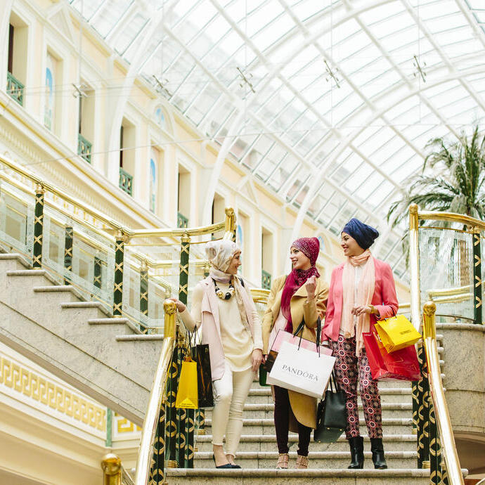 Tres mujeres con bufandas caminando con bolsas de la compra