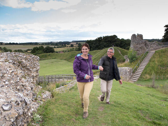 A couple walking along the ruins of Castle Rising West in Norfolk