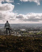 Un hombre de pie en la cima de una colina con vistas a la ciudad