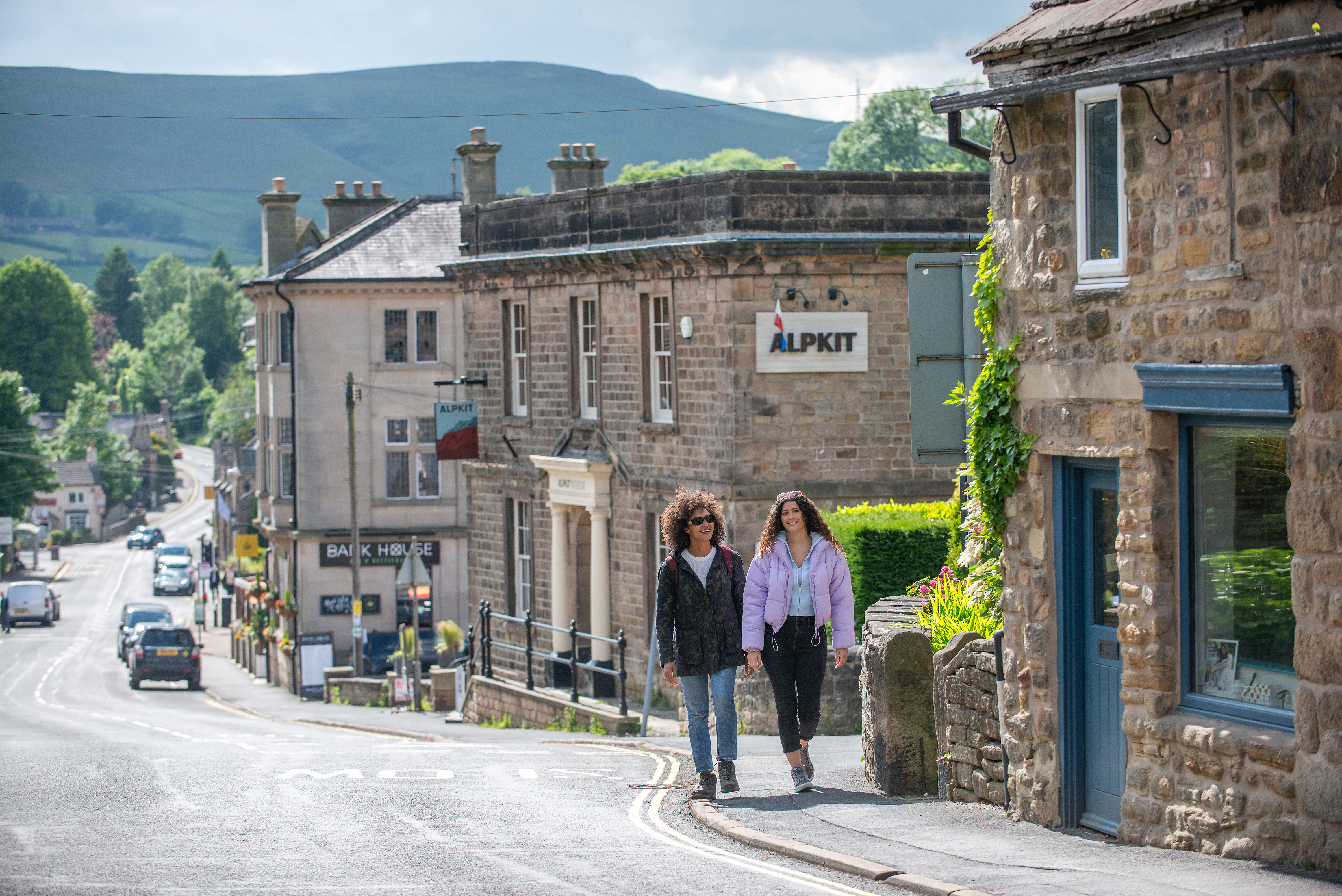 Two women walk through a village set in countryside