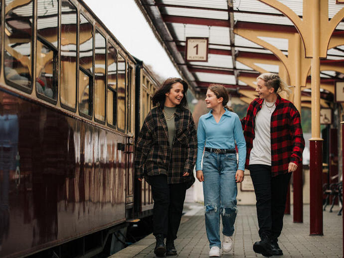 Three people walking along a train platform.
