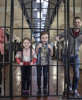 Family pretending to be locked in a cell at Crumlin Road Gaol, Belfast