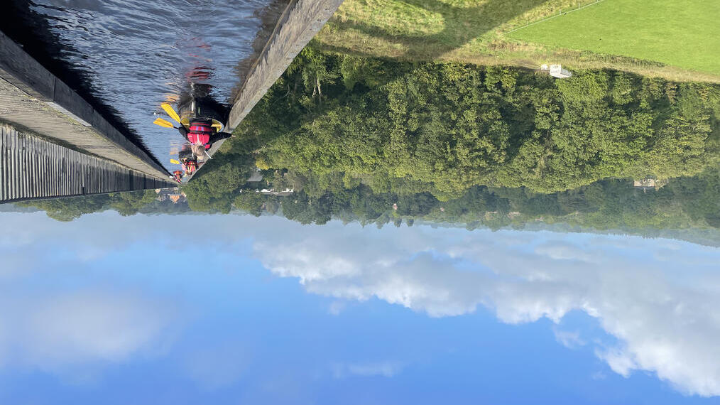 Eine Gruppe paddelt mit Kajaks über einen Viadukt mit malerischem Blick auf den Snowdonia/Eryri-Nationalpark