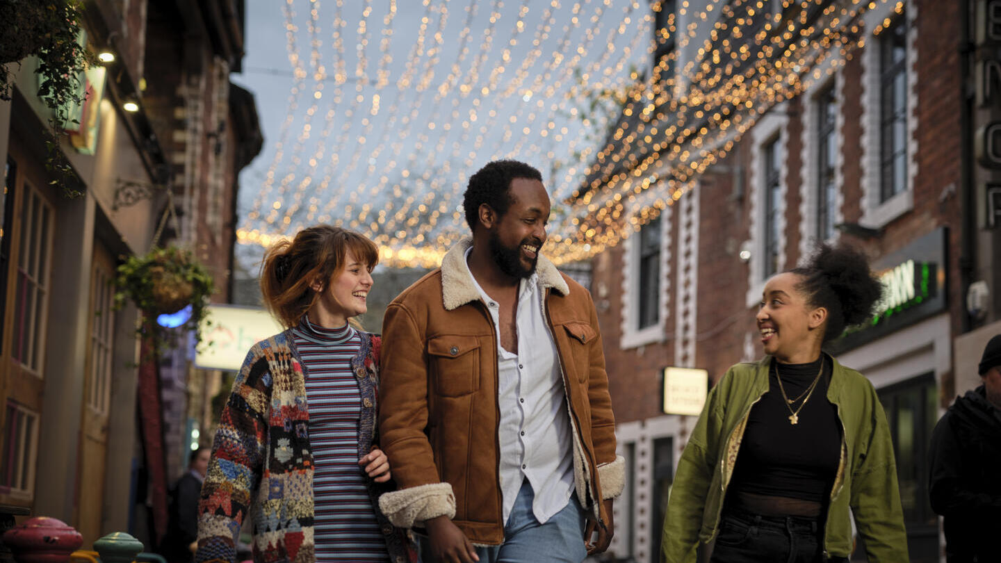 Friends exploring a cute shopping laneway lit up with fairy lights.
