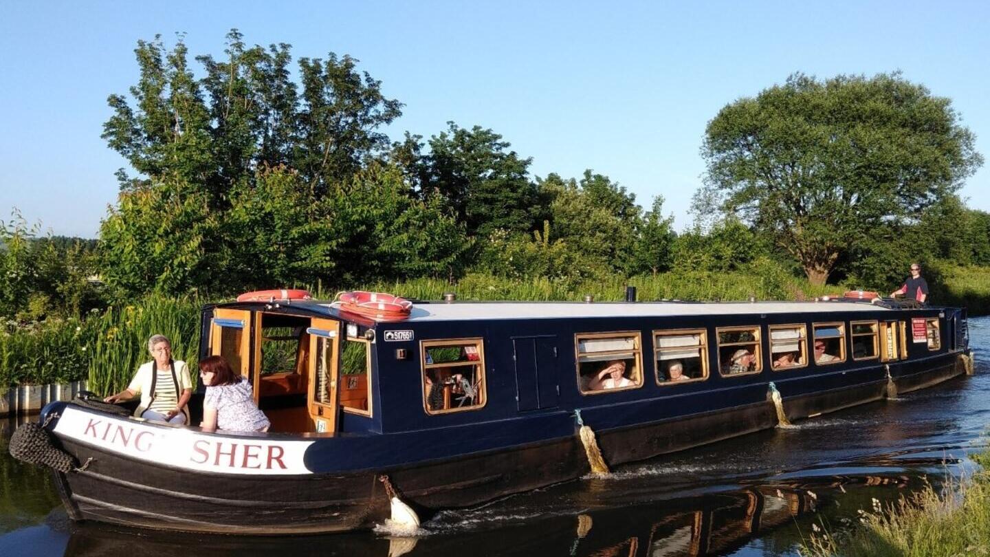 A group of people onboard a barge sailing down a river in Lancashire