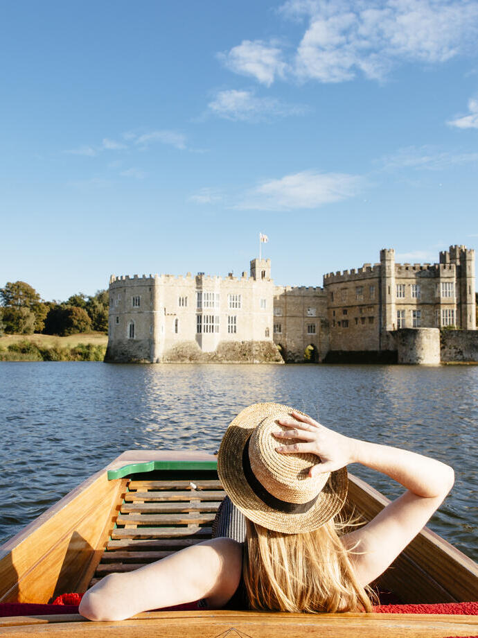 Woman in a punt on the moat looking towards castle