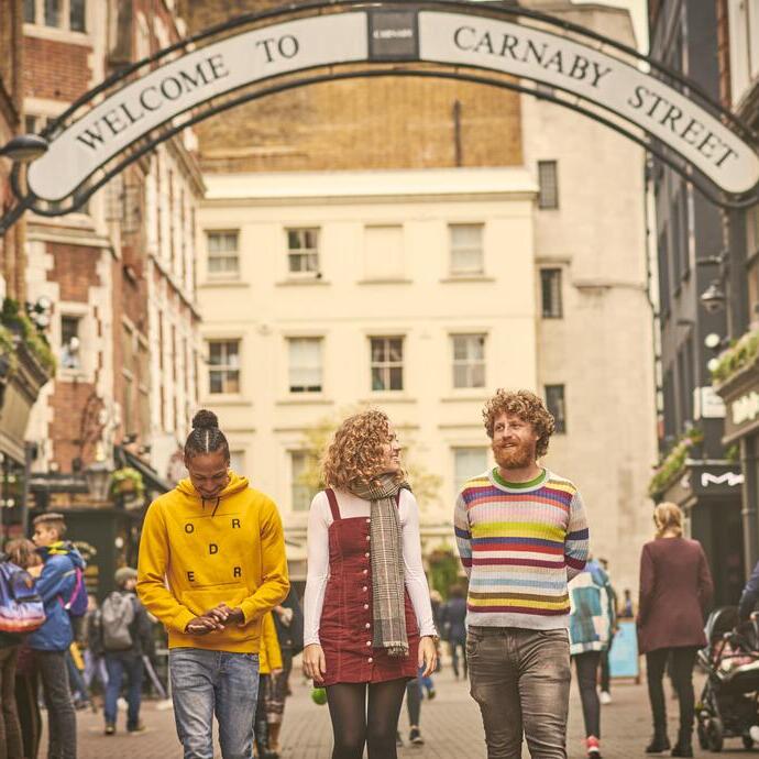 امرأة ورجلان يسيران في شارع للتسوق