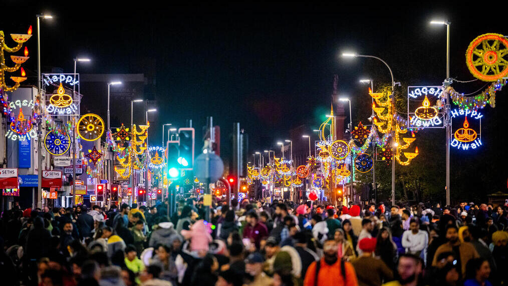 Nigh scene of crowd at festival, with luminaries hanging over the street
