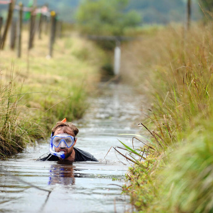 Un plongeur dans la tourbière pataugeant dans un canal