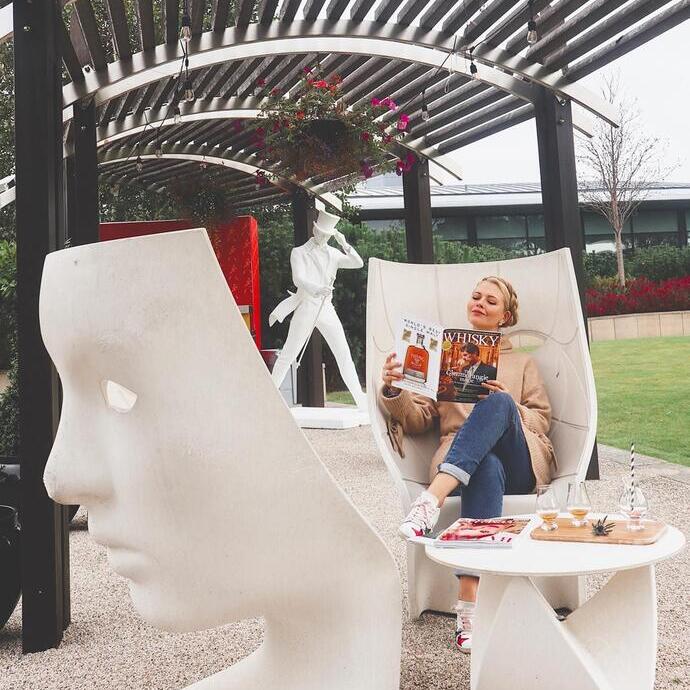 Una donna seduta che legge una rivista, fuori dal The Glasshouse, Edimburgo, Scozia