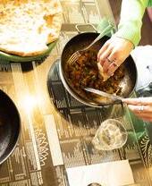 A curry dish and naan bread on the side served at a restaurant