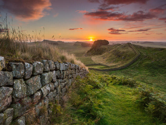 View along long stone wall over the fields at sunset